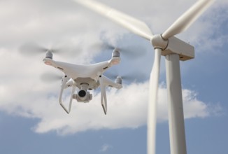 Unmanned aircraft system (UAV) quadcopter drone in the air surveying wind turbines.