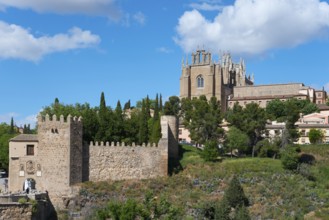 Medieval cityscape with church, city walls and trees under a blue sky with clouds, Puente de San