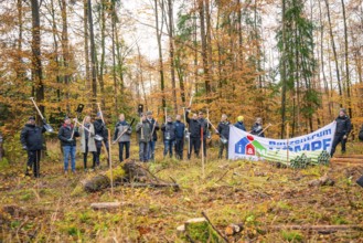 Group posing for a photo with a banner in autumn forest, tree planting campaign, Waldbike Calw,