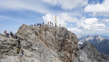 Tourists queue up for the summit of the Zugspitze, summit with golden summit cross, overtourism,