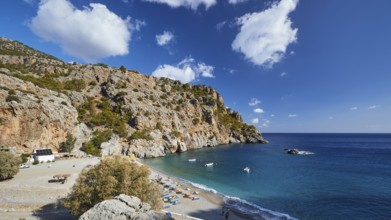 Panorama of a rocky coastline with beach and offshore boats under a blue sky, Ahata Beach, Ahata,