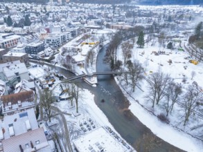 Snow-covered river course with bridges and surrounding town buildings in a wintry setting, Nagold,