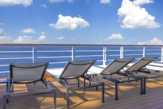 Cruise ship deck and lounge chairs overlooking beautiful ocean on a cruise vacation in Caribbean