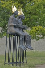 Sculpture Enthroned by Volkmar Kühn 2021, three bishops with golden mitres sitting on stools, row,