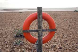 Red life saving ring Shingle Street beach, Suffolk, England, UK