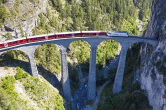 Drone shot of train passing the Landwasserviadukt near Filisur, red train of Bernina Express,