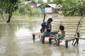 Morigaon, India. 4 July 2024. Father with his daughter eating food, in a flood affected village in