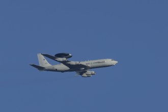 Boeing E-3 Sentry AWACS military aircraft of NATO flying in a blue sky, England, United Kingdom,