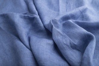 Fragment of blue linen tissue. Side view, natural textile background and texture. wave concept,