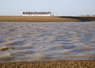 White terrace of Coastguard Cottages, beach and sea viewed from offshore, Shingle Street, Suffolk,