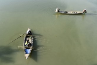 Fishermen fishing sitting on a boat in a lake using fishing rods at a village in Barpeta district