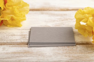 Gray business card with iris yellow flowers on white wooden background. side view, copy space,