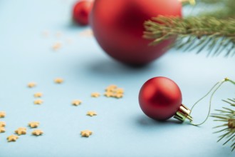 Christmas or New Year composition. Decorations, red balls, fir and spruce branches, on a blue paper