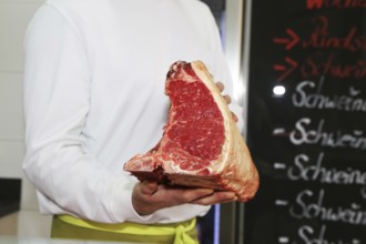 Butcher holds a dry aged T-bone steak in his hand