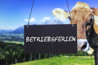 Symbolic image company holidays: Sign with the inscription BETRIEBSFERIEN in front of an alpine