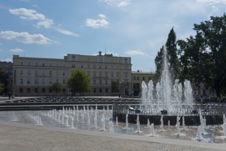 Lively public square with impressive fountain and surrounding buildings, fountain, post office,