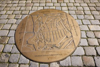 Fountain of the Materni Hospital, bronze fountain slab, cobblestone pavement, street An der