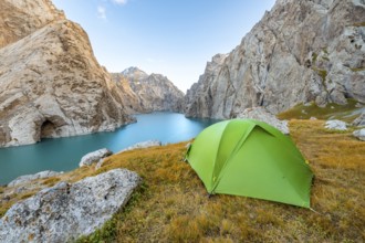 Green tent at the turquoise mountain lake Kol Suu with rocky steep mountains, Kol Suu Lake, Sary