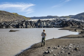 Tourist on the shore of a glacier lagoon, glacier tongue and lake, Sólheimajökull, South Iceland,