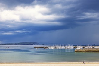 View at the coast and a boat marina with dark thunderclouds at sea in Bretagne, Morgat, Crozon,