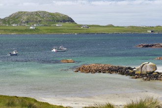 Some boats on the sea in front of a rocky coast, island with houses, view of Iona, Port of