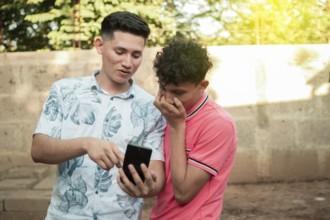 A young man explaining with his cell phone to a young man, A young man showing his cell phone to