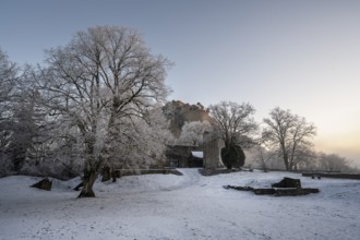 The snow-covered Karlsbastion of the Hohentwiel fortress ruins in front of sunrise on a cold winter