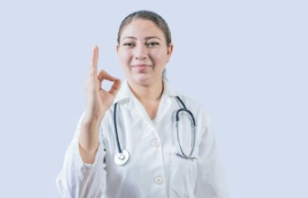 Beautiful female doctor gesturing approval isolated. Smiling female doctor approving and