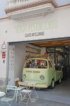 Retro ice cream parlour with green VW bus and outdoor seating in front of the shop, pedestrian