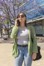 Businesswoman talking on smartphone while walking in a city park, enjoying a sunny day