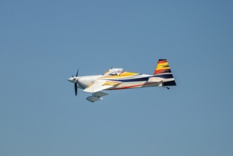 Stunt aerobatic plane performing stunts in blue sky. Concept of speed, difficulty, precision, risk,