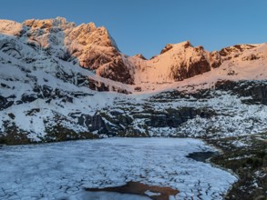 Aerial view of icy lake in front of steep mountains, winter, sunrise, Storvatnet, Flakstadoya,