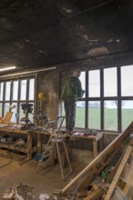 Elderly man standing on a workbench and repairing a window in a workshop, Mecklenburg-Vorpommern,