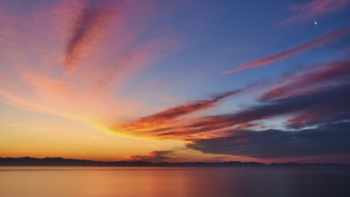 Colourful sky with crescent moon at sunrise over the sea, Mani Peninsula, Peloponnese, Greece,