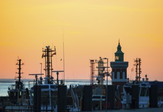 Harbour at sunset with various boats and the sea in the background, the sky in bright orange,