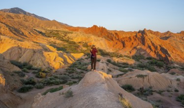 Hiker between red rocks, canyon of eroded sandstone formations, red and orange sandstone rocks,