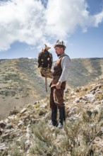 Traditional Kyrgyz eagle hunter hunting in the mountains in a dry landscape, near Kysyl-Suu, Issyk