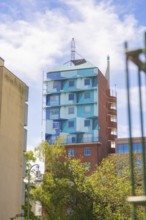 A colourfully painted skyscraper with an unusual design against a clear blue sky surrounded by