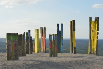 A creative art installation of colourfully painted wooden posts with abstract patterns against a