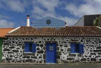 Former whaler's stone house with blue shutters and door, traditional tiled roof, narrow chimney,