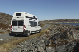 Camper/caravan on a lonely coastal road through the tundra to Hamningberg (in the background) on