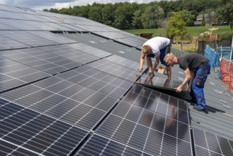 Installation of solar modules on the roof of a barn on a farm, over 210 photovoltaic modules are