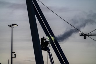 Worker cleans a bridge pier with a high-pressure cleaner on a cherry picker at the Erasmus Bridge