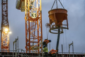 Concrete work, at dusk, on a large construction site building a residential and commercial complex,