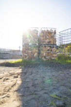 Stacked pieces of wood in metal frames in a meadow with sunshine and shade, refugee accommodation