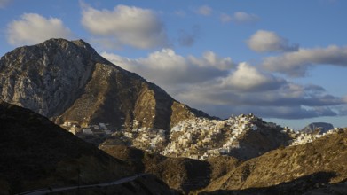 A small village stretches in the mountains under a sky with dramatic clouds, Colourful mountain