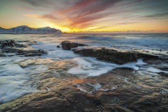 Long exposure, sunset in winter at Skagsanden, rocks washed over by the sea on the beach at