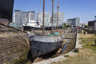 Historic sailing ship moored in the harbour, surrounded by industrial architecture, Liverpool