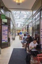 Inner courtyard of a café with people eating and working under a glass ceiling, Cork