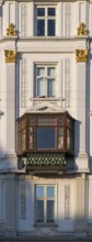 Neoclassical house façade with partially gilded stucco decorations and a projecting bay window,